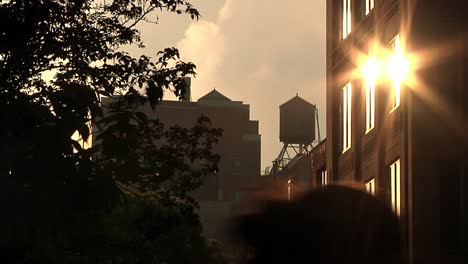 Golden-Yellow-Reflection-Of-Sun-On-Apartment-Building-With-Water-Tower-In-The-Distance-In-New-York