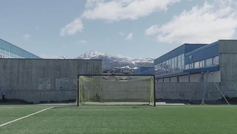 Group-Of-Teenagers-Behind-Goal-Posts-On-Empty-Pitch-With-Snow-Capped-Mountains-In-The-Distant