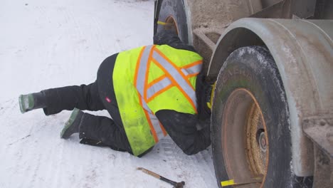 Tuck-driver-inspects-tires-on-dual-axle-gravel-truck