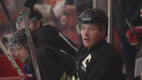 Hockey-captain-sits-on-bench-with-team