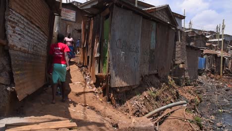 People-walk-near-a-river-of-sewage-in-the-Kenyan-slum-of-Kibera-in-Nairobi