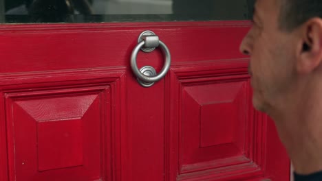 Man-knocks-on-red-door-and-delivers-package-to-woman