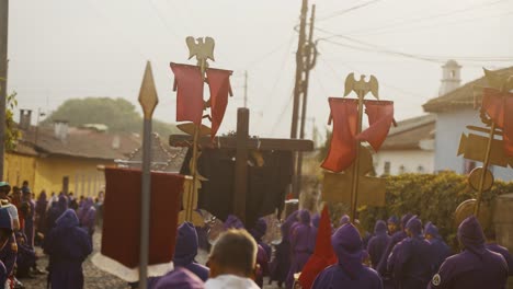 Cucuruchos-In-Purple-Tunicas-Carrying-Signs-And-Wooden-Cross-At-The-Holy-Week-Procession-In-The-Street-Of-Antigua-In-Guatemala