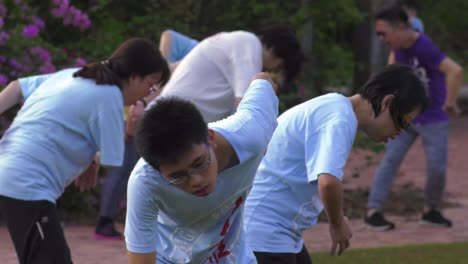Young-boy-among-group-of-people-practicing-Tai-Chi,-in-Singapore---Medium-close-up-shot