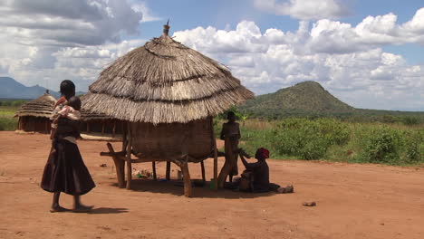 Madre-E-Hijo-Sentados-A-La-Sombra-Bajo-Una-Pequeña-Cabaña-Con-Techo-De-Paja-En-Ruanda