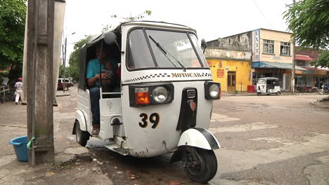 Passenger-Getting-Into-White-Three-Wheeled-Motor-Car-On-Street-In-Iquitos,-Peru