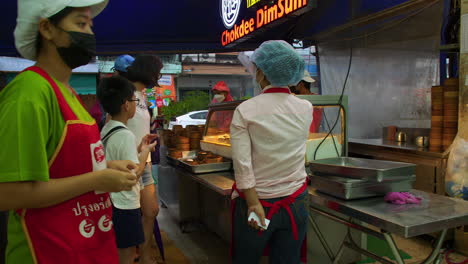 Customers-at-ASEAN-night-bazaar-buying-Thai-street-food,-Hat-Yai,-Thailand
