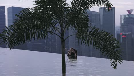 Two-Friends-Posing-For-Photos-At-Infinity-Pool-In-Singapore-Viewed-Through-Tree
