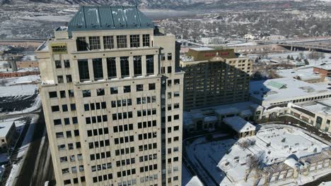Aerial-view-Ascending-shot,-Scenic-view-Wells-Fargo-Tower-in-Downtown-Colorado-snow-covered-streets-and-highway-in-the-background