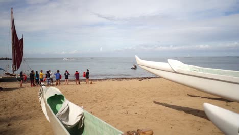 View-from-resting-canoes-to-group-of-students-preparing-for-sailing-on-a-Catamaran-in-Oahu,-Hawaii---Wide-static-shot