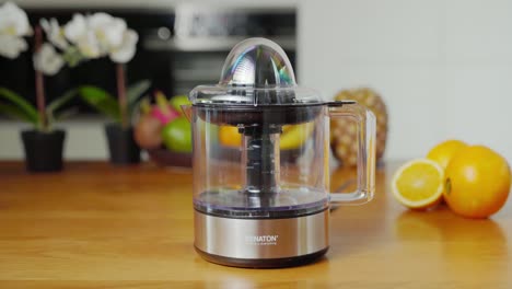 Electric-juicer-on-kitchen-counter-used-for-squeezing-fruits-into-juice,-tilting-view
