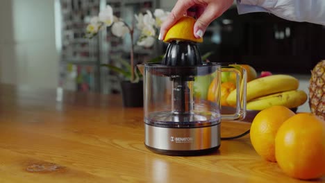 Frau-In-Der-Küche-Benutzt-Einen-Elektrischen-Entsafter,-Um-Frische-Orangen-Auszupressen-Und-Orangensaft-Zuzubereiten