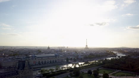 Aerial-cinematic-drone-Paris-France-Eiffel-Tower-famous-historic-landmark-from-a-far-distance-Seine-River-late-afternoon-summer-fall-romantic-blue-sky-bright-sun-surrounded-by-buildings-forward-motion