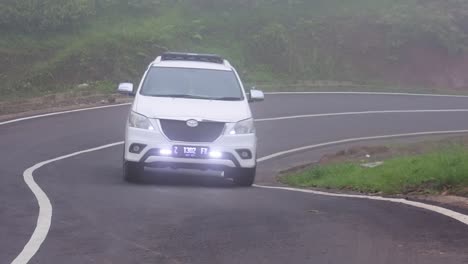 white-car-Toyota-going-through-sharp-turns-on-highway-in-hills-during-fog