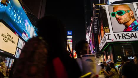 Timelapse-and-motionlapse-of-timesquare,-new-york,-giant-screens-with-advertising-at-night-while-people-and-vehicles-circulate-on-the-street,-street-lifestyle