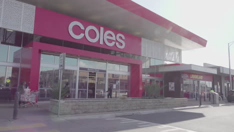 The-camera-captures-a-view-of-the-exterior-of-a-Australian-local-shopping-center,-with-customers-entering-through-its-doors