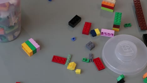 Slow-panning-shot-of-lego-building-blocks-scattered-across-a-table