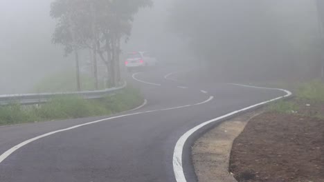 Coche-Blanco-Pasando-Por-Curvas-Cerradas-En-La-Autopista-En-Las-Colinas-Durante-La-Niebla