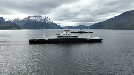 Electric-ferries-Eidsfjord-and-Gloppefjord-meeting-each-other-in-middle-of-Nordfjord-at-Anda-Lote-connection---Aerial-showing-side-of-ships-and-scenic-background---Norway