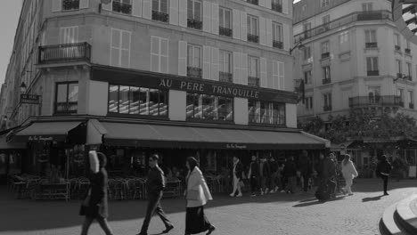 Gente-Caminando-Por-La-Calle-Frente-Al-Restaurante-Francés-Au-pere-Tranquille-Con-Una-Gran-Terraza-En-París,-Francia