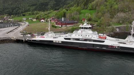 Aerial-around-ferry-Eidsfjord-from-Fjord-1-company-while-alongside-Lote-ferry-pier-in-Nordfjord-Norway---Aerial-showing-electrical-battery-powered-ferry-while-charging