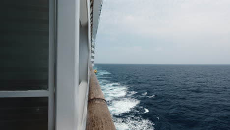 The-side-of-a-cruise-ship-and-its-wake-as-it-sails