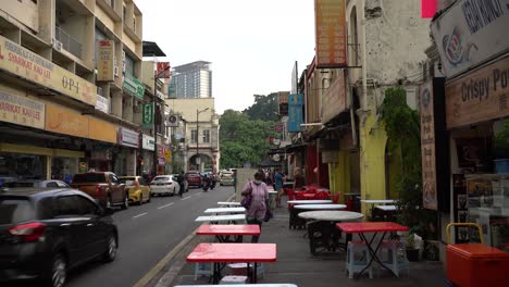 Sights-of-street-traffic-and-empty-tables-from-local-coffee-shops-ready-for-business-in-Chinatown,-Kuala-Lumpur,-Malaysia