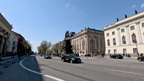 View-Of-Equestrian-statue-of-Frederick-the-Great-In-Berlin-With-Light-Traffic-And-Cyclists-Going-Past-On-Sunny-Day-In-Berlin