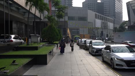 Morning-scene-of-people-walking-outside-the-Grand-Millennium-Hotel-and-against-the-background-of-the-famous-shopping-mall,-Pavilion-Kuala-Lumpur,-Malaysia