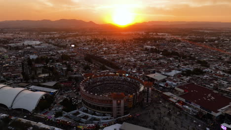 Aerial-view-around-the-Plaza-de-Toros-San-Marcos,-bullfighting-ring,-sunset-in-Aguascalientes,-Mexico