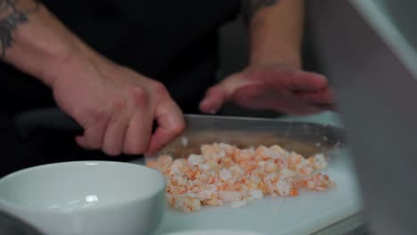 Mexican-chef-inside-restaurant-kitchen-cut-chop-slice-fresh-shrimps-in-pieces