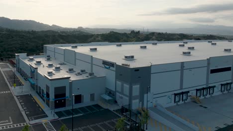 Arial-drone-shot-moving-across-the-exterior-of-an-Amazon-Distribution-Warehouse-based-in-Santa-Clarita,-California