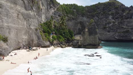 Aerial,-Tourists-relaxing,-sunbathing-and-swimming-at-Diamond-Beach-in-Nusa-Penida-Island,-Bali---Indonesia