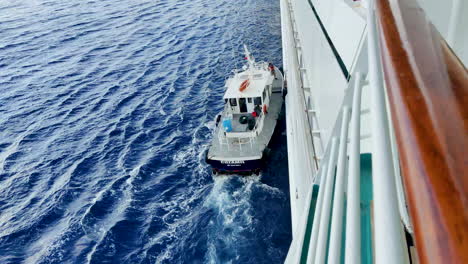 A-pilot-boat-from-Cozumel-gracefully-maneuvers-through-the-water,-attached-to-a-cruise-ship's-side-for-operational-purposes-|-smooth-and-safe-navigation-as-the-cruise-ship-approaches-its-destination