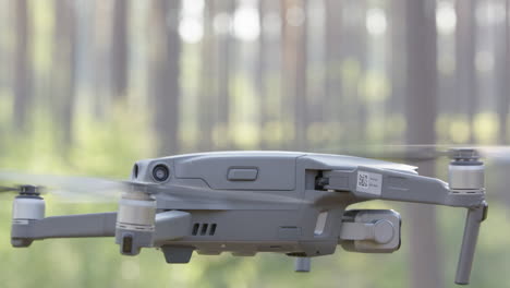 DJI-drone-hovering-and-panning-in-woodland,-close-up-static-shot