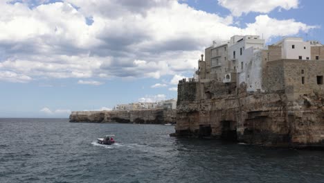Tourist-boat-trip-near-picturesque-old-Polignano-rocky-coast-on-vacation