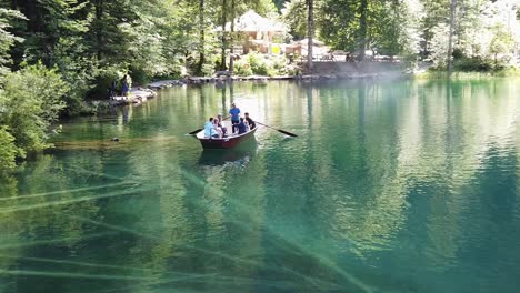 Turistas-Disfrutando-De-Un-Paseo-En-Barco-Con-Fondo-De-Cristal-Sobre-Aguas-Cristalinas-De-Color-Turquesa-Del-Famoso-Lago-Alpino-Blausee-En-Kandersteg,-Suiza