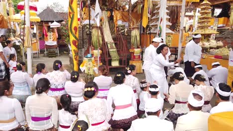 Revered-Priestess-Blesses-Devotees-in-Balinese-Hindu-Temple-Ceremony,-Colorful-Ornaments-Displayed