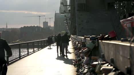 Cinematic-Shot-Of-Cyclist-Riding-Past-Love-Locks-On-Hohenzollern-Bridge-With-Beautiful-Sun-Light