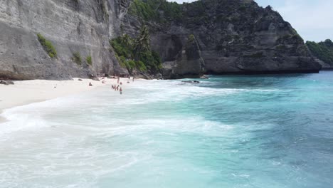 Tiefflug-über-Brandungswellen-Und-Touristen,-Die-Sich-Am-Diamond-Beach-Auf-Der-Insel-Nusa-Penida-Entspannen
