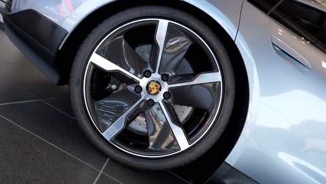 Up-close,-the-image-reveals-a-brand-new,-gleaming-Porsche-car,-with-a-focus-on-its-shiny-wheel