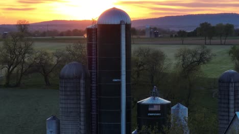 Luftaufnahme-Eines-Ländlichen-Bauernhofs-Mit-Silos-In-Den-USA-Während-Des-Frühlingssonnenuntergangs