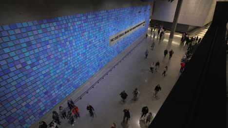 Visitors-in-interior-of-National-September-11th-Memorial-and-Museum-with-inscription-on-blue-wall,-New-York