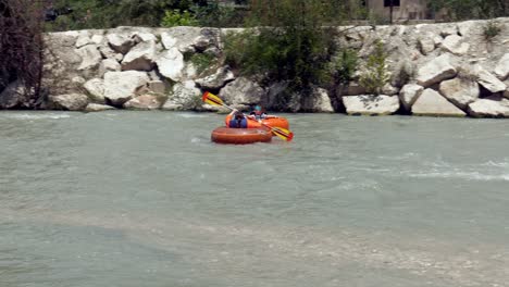 Fun-adventure-tourists-in-river-rafting-tubes-speed-down-rapid-flowing-river