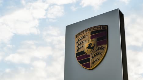 Porsche-car-dealership-sign-against-cloudy-sky.-Time-lapse