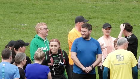 Group-of-runners-meeting-talking-and-supporting-each-other-in-local-park-field-at-start-of-their-fitness-run