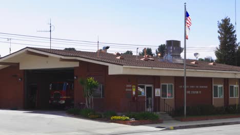 Static-shot-of-a-Los-Angeles-County-firehouse-with-flags-waving-in-the-breeze-and-traffic-passing-by