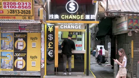 A-customer-is-seen-at-a-foreign-currency-exchange-and-money-change-company-shop-as-pedestrians-walk-past-the-frame