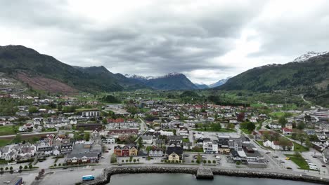 City-of-Nordfjordeid-Norway---Backward-moving-aerial-showing-full-panoramic-view-of-village-from-seaside-and-above-the-Eidsfjorden-fjord