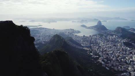 Aerial-view-overlooking-the-city,-turning-towards-the-Cristo-Redentor-statue,-in-sunny-Rio-de-Janeiro,-Brazil